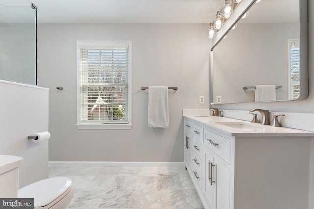 bathroom with toilet, marble finish floor, baseboards, and a sink