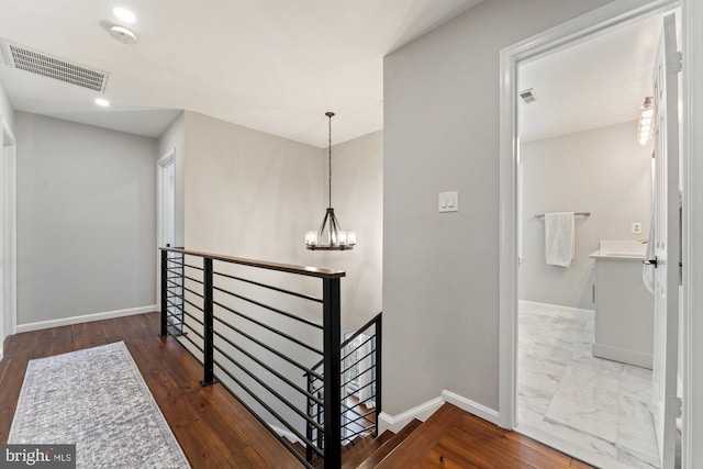 corridor featuring a notable chandelier, an upstairs landing, visible vents, and baseboards