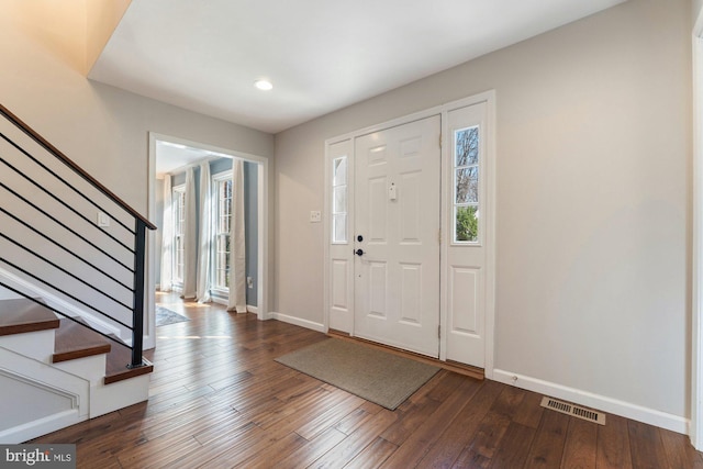 entryway with dark wood finished floors, recessed lighting, visible vents, stairway, and baseboards