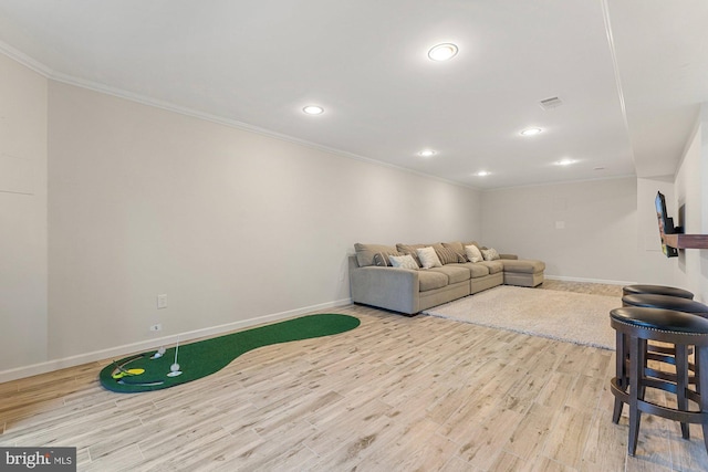 living area with ornamental molding, wood finished floors, visible vents, and baseboards