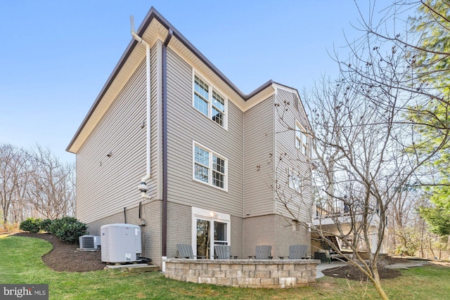 rear view of property featuring central AC, brick siding, a lawn, and a patio area