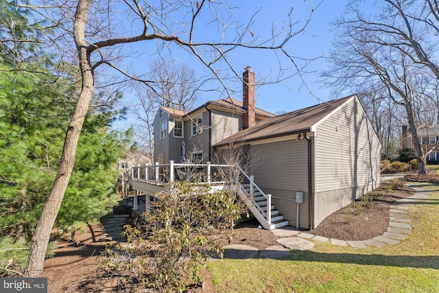 view of property exterior featuring a chimney, a deck, and stairs