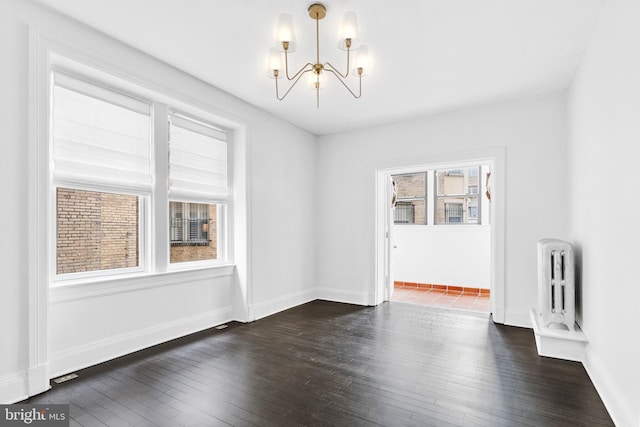 unfurnished dining area with a chandelier, baseboards, dark wood finished floors, and radiator heating unit