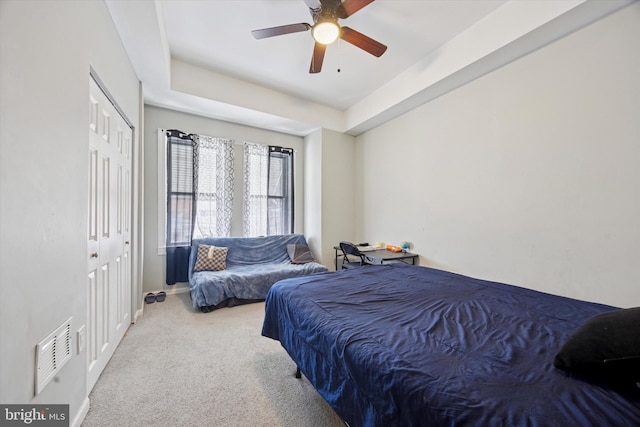 carpeted bedroom with a closet, visible vents, and a ceiling fan