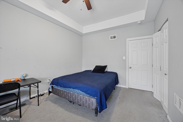 carpeted bedroom featuring a raised ceiling, baseboards, and visible vents