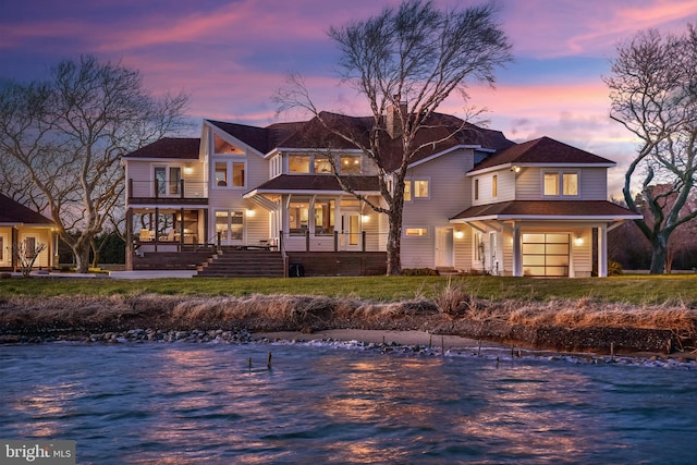 rear view of property featuring covered porch, a water view, and a balcony