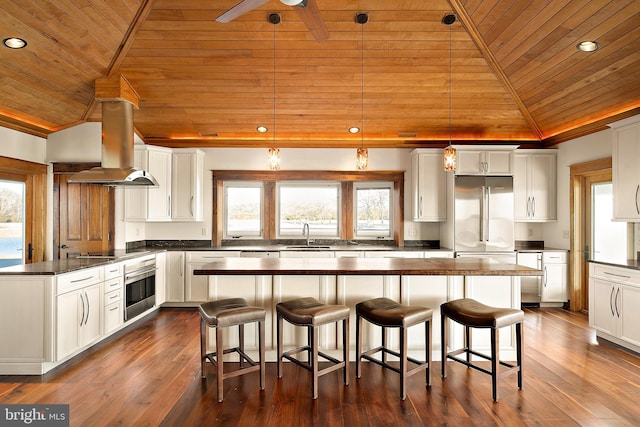 kitchen featuring stainless steel appliances, white cabinetry, vaulted ceiling, a kitchen island, and island range hood