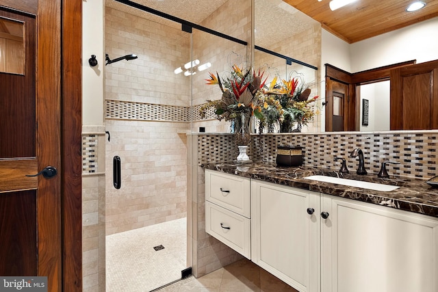 bathroom featuring a stall shower, backsplash, vanity, and tile patterned floors