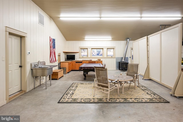 playroom with concrete flooring, visible vents, and a wood stove