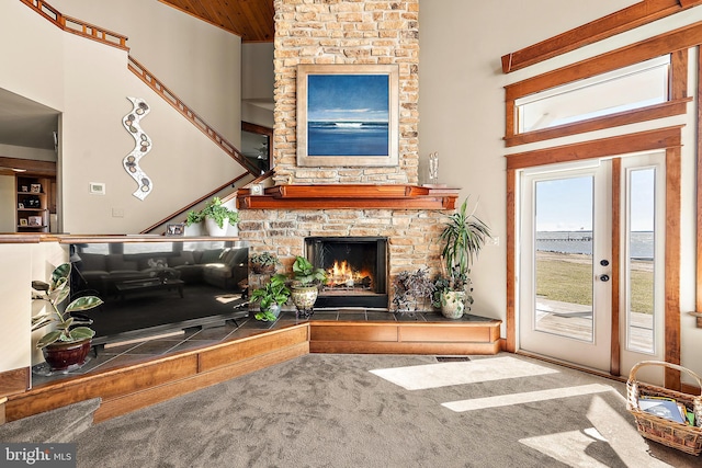 carpeted living area featuring a fireplace and a towering ceiling