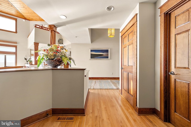 hall with light wood-type flooring, visible vents, and baseboards