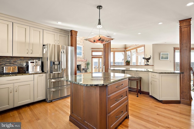 kitchen featuring light wood-style floors, dark stone counters, a kitchen island, and stainless steel fridge with ice dispenser