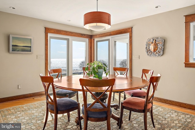 dining area with light wood-type flooring, visible vents, and baseboards