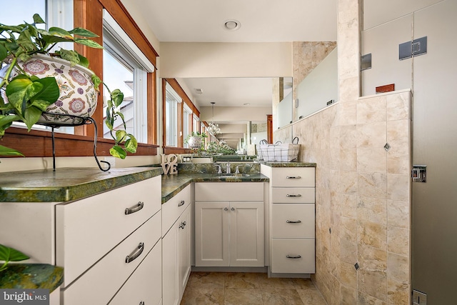 kitchen featuring a sink, tile walls, and white cabinetry