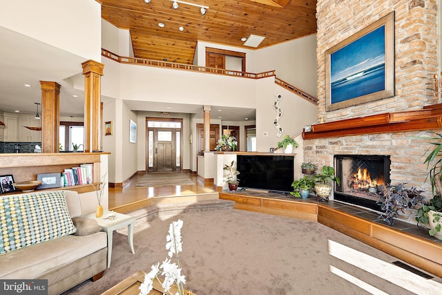 living room featuring wooden ceiling, ornate columns, a high ceiling, and visible vents