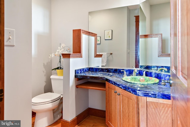 bathroom featuring baseboards, vanity, and toilet