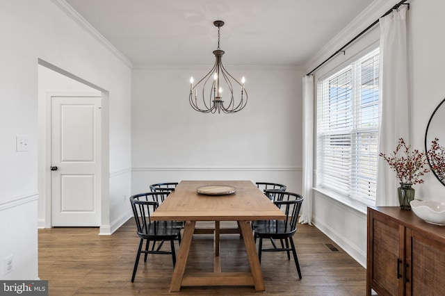 dining area with ornamental molding, visible vents, a notable chandelier, and wood finished floors