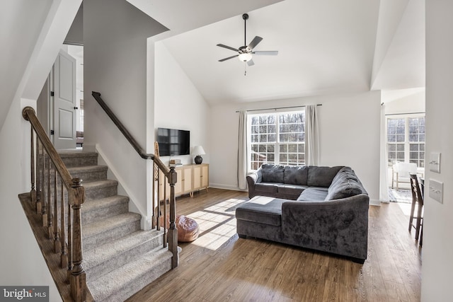 living room featuring a healthy amount of sunlight, stairs, wood finished floors, and lofted ceiling