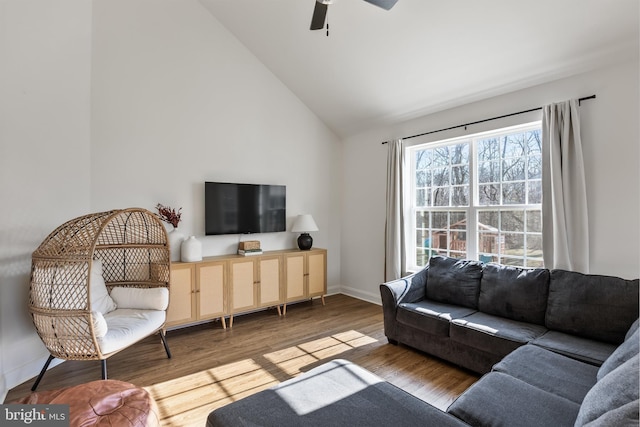 living room featuring high vaulted ceiling, ceiling fan, baseboards, and wood finished floors