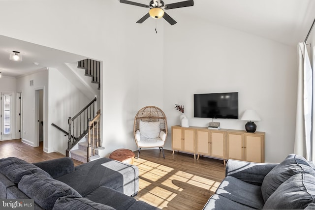 living room with baseboards, stairs, a ceiling fan, and wood finished floors