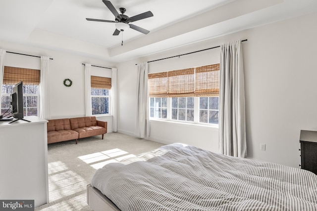 bedroom with baseboards, a raised ceiling, a ceiling fan, and light colored carpet