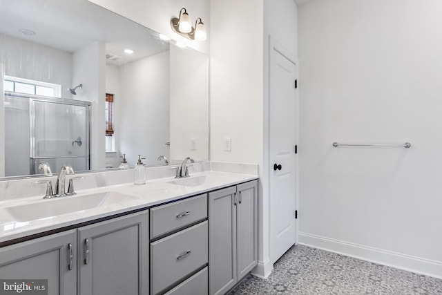 bathroom with a sink, a shower stall, baseboards, and double vanity