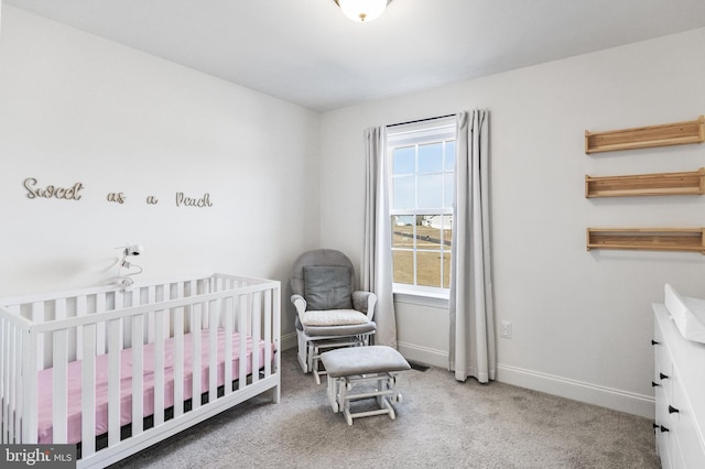 carpeted bedroom featuring a nursery area and baseboards