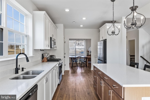 kitchen with light countertops, appliances with stainless steel finishes, a sink, and white cabinets