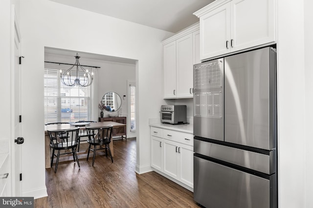 kitchen featuring dark wood-style flooring, white cabinetry, light countertops, freestanding refrigerator, and an inviting chandelier