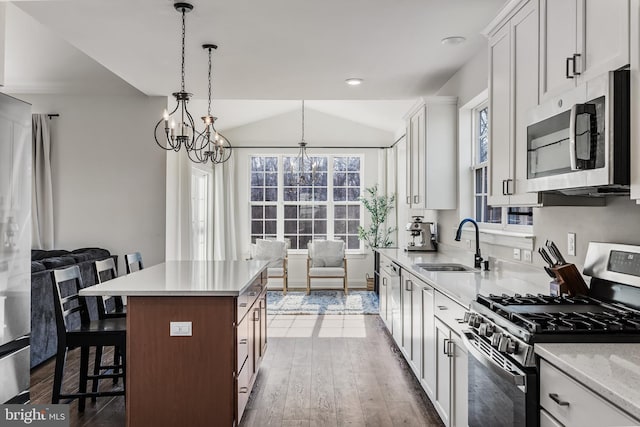 kitchen with lofted ceiling, a breakfast bar area, dark wood-type flooring, a sink, and appliances with stainless steel finishes