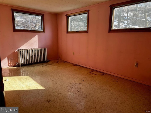 unfurnished room with ornamental molding, baseboards, and radiator heating unit