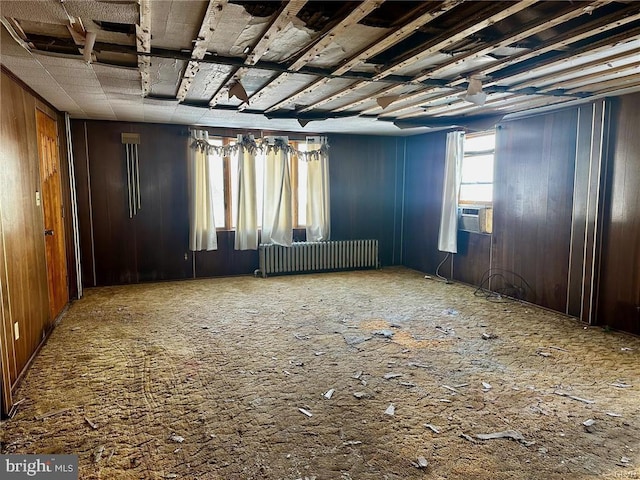 empty room featuring wood walls and radiator