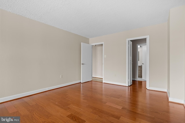 unfurnished room featuring a textured ceiling, baseboards, and wood finished floors