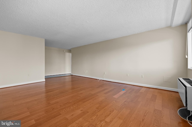 unfurnished living room with a textured ceiling, a baseboard radiator, light wood-style flooring, and baseboards