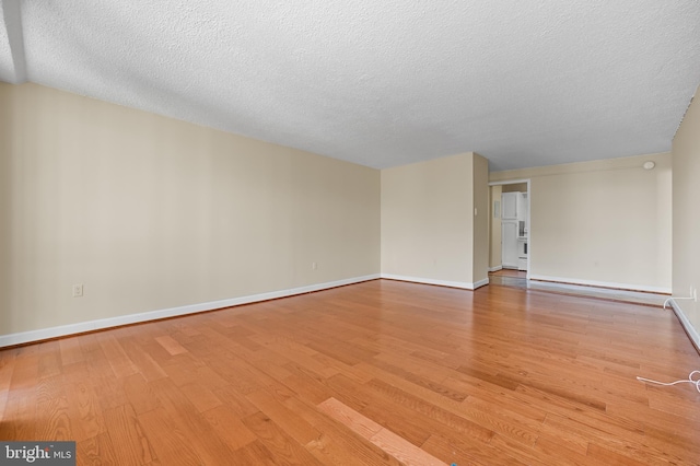 unfurnished room featuring light wood-style floors, a baseboard radiator, a textured ceiling, and baseboards