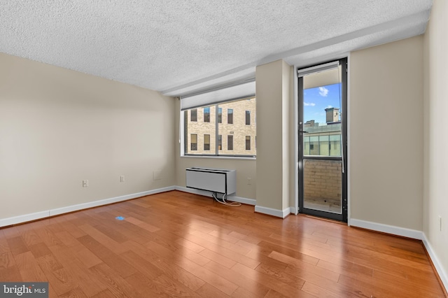 unfurnished room featuring a textured ceiling, radiator, wood finished floors, and baseboards