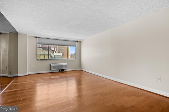 empty room with a textured ceiling, baseboards, and wood finished floors