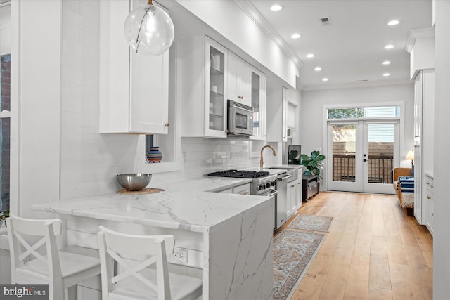 kitchen with stainless steel appliances, visible vents, white cabinetry, decorative backsplash, and light stone countertops