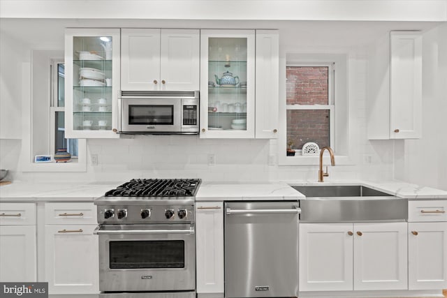 kitchen with stainless steel appliances, a sink, and white cabinets