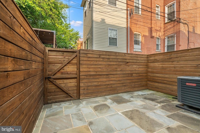 view of patio / terrace featuring central AC unit, fence, and a gate