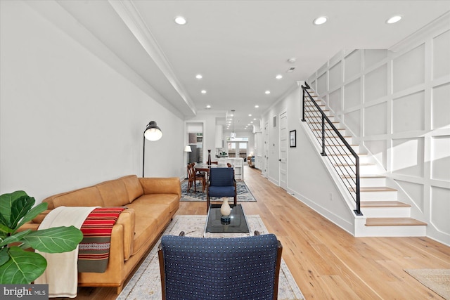 living room featuring a decorative wall, recessed lighting, light wood-style floors, stairway, and crown molding