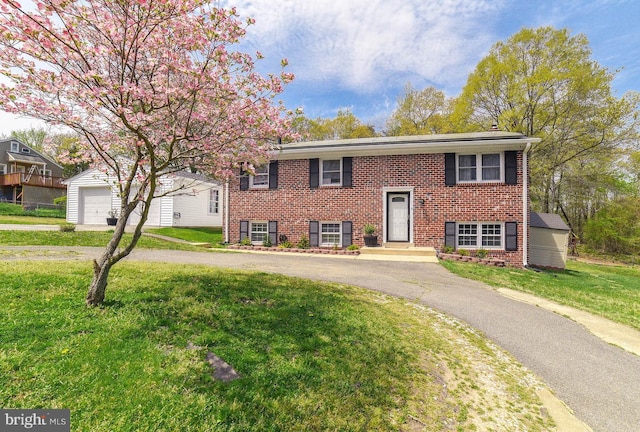 bi-level home with an outbuilding, driveway, brick siding, and a front lawn