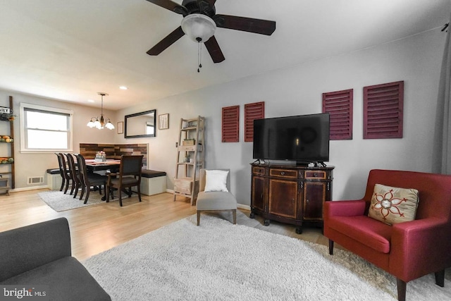 living room featuring recessed lighting, baseboards, wood finished floors, and ceiling fan with notable chandelier