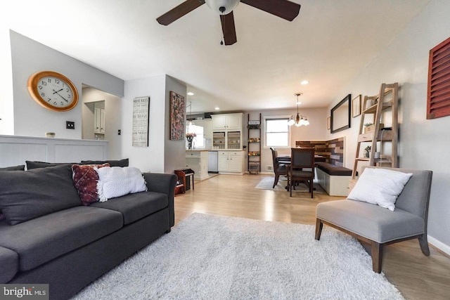 living area with light wood-type flooring, baseboards, recessed lighting, and ceiling fan with notable chandelier