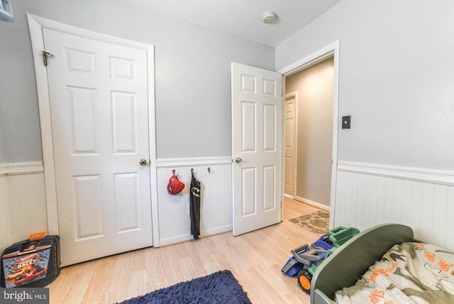 bedroom with wood finished floors and wainscoting