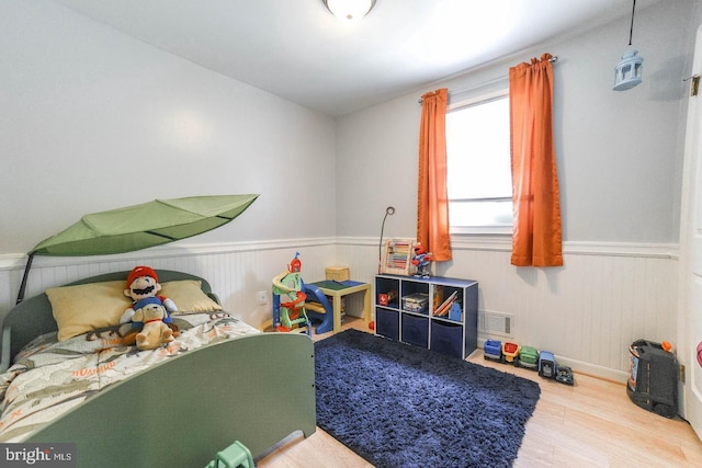 interior space with wainscoting, visible vents, and wood finished floors