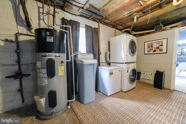 laundry area with laundry area, hybrid water heater, concrete block wall, and stacked washer / drying machine