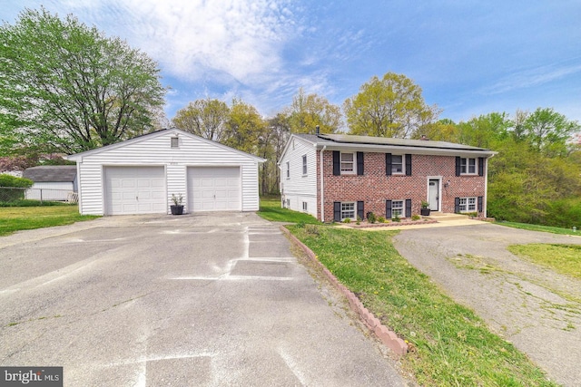 split foyer home featuring a garage, an outbuilding, brick siding, and a front yard