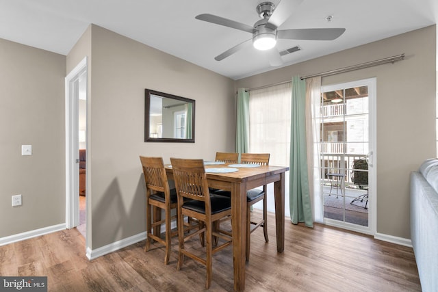 dining space featuring visible vents, baseboards, wood finished floors, and a ceiling fan