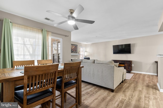 dining space featuring a ceiling fan, baseboards, visible vents, and light wood finished floors